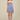 Woman wearing a strapless, pleated blue dress against a beige background