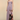 A woman models a strapless floor-length gown in a studio setting. The dress is a muted dusty lavender-purple with a dramatic abstract print in brown, black, and pink on the lower skirt.