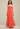 Woman wearing a strapless, ruched coral gown against a plain background