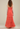 Woman wearing a coral strapless gown against a plain background