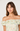 Woman wearing a floral off-shoulder top against a plain background