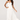 Woman wearing a white strapless dress with pleated skirt on a white background