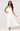Woman wearing a white strapless dress with pleated skirt on a white background