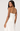 Woman wearing a white strapless dress with a pleated skirt on a plain background