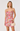 Woman wearing a floral dress holding a beige handbag on a white background