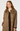 A woman wearing a brown and beige houndstooth patterned coat over a dark brown top, photographed against a plain light gray studio background.