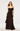 A woman modeling a long black ruffled spaghetti-strap dress against a plain light gray studio background.