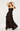 A woman modeling a dark brown ruffled spaghetti-strap maxi dress with a tiered skirt, posed against a clean white studio background.