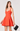 Woman wearing an orange dress holding a black handbag on a white background
