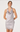 A woman modeling a light silver-gray satin halter slip dress with a cowl neckline, lace trim at the hem, and a matching lace band at the waist, set against a plain light gray studio background.