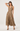 A woman modeling a sleeveless leopard-print halter midi dress with a flared skirt, paired with black strappy sandals, against a plain light gray studio background.
