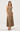 A woman modeling a sleeveless halter-neck maxi dress with an all-over leopard print pattern in brown and beige tones, paired with black strappy sandals, against a plain light gray studio background.