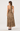 A woman shown from the back wearing a leopard-print halter maxi dress with a tie-neck detail, photographed against a plain light gray studio background.