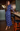 A woman wearing a long-sleeved navy blue maxi dress with a white floral pattern, standing in a bar environment next to a counter with two wine glasses.