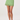 Green mini skirt with lace trim worn by a person on a white background