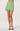 Green mini skirt with lace trim worn by a person on a white background