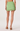 Green mini skirt with lace details worn by a person on a white background