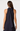 A woman shown from the back wearing a sleeveless halter dress with a bow at the neck and a small pink polka dot pattern on a dark navy base, photographed against a light gray studio background.