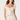 A woman modeling a cream-colored two-piece set featuring a ruffled sweetheart top with a tie-front detail and a matching textured skirt, set against a plain light background.