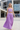 A woman modeling a lavender two-piece outfit consisting of a cropped tank top and matching high-waisted maxi skirt, set against a modern concrete and glass stadium background.