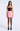 A model wearing a strapless mini dress with a dark brown sequined bodice and a light pink skirt, paired with sheer black tights and black high heels, against a light gray studio background.