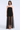 A woman modeling a strapless black tulle dress with a sheer overskirt and black strappy high-heeled sandals against a light gray studio background.