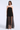 A woman modeling a strapless black tulle dress with a sheer, flowing skirt against a light gray studio background.