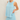 Woman wearing a light blue sleeveless top and shorts set against a plain background
