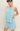 Woman wearing a light blue sleeveless top and shorts set against a plain background