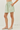Person wearing a green and white striped skirt on a plain background