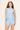 Woman wearing a light blue lace top and shorts set on a plain background
