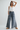 Woman wearing a white top and blue wide-leg jeans on a plain background