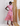 Woman wearing a colorful patterned dress standing against a textured wall.