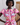 Woman wearing a colorful patterned dress with a plain background