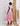 Woman wearing a colorful patterned dress standing against a textured wall.