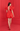 Woman wearing a red dress with large sleeves against a red wall.
