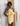 Woman wearing a yellow lace dress against a textured wall.