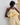 Woman wearing a yellow lace dress against a textured wall.