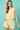 Woman wearing a light green sleeveless top and shorts set against a teal background