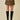 A model wearing a brown and black zebra-print wrap mini skirt with black knee-high leather boots, standing against a solid beige background.