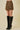 Person wearing a zebra print skirt and black knee-high boots on a beige background