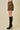 Person wearing a zebra print skirt and black knee-high boots on a beige background