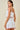Woman wearing a white dress with red trim on a beige background