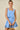 Woman wearing a light blue dress with floral cutouts on a beige background