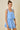 Woman wearing a light blue dress with floral cutouts on a beige background