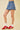 Person wearing a denim skirt and red sneakers on a beige background