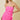 Woman wearing a strapless pink dress with white trim on a beige background