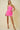Woman wearing a pink strapless dress against a beige background