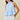 Woman wearing a light blue top and white shorts on a beige background