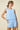 Woman wearing a light blue sleeveless top and shorts set on a beige background